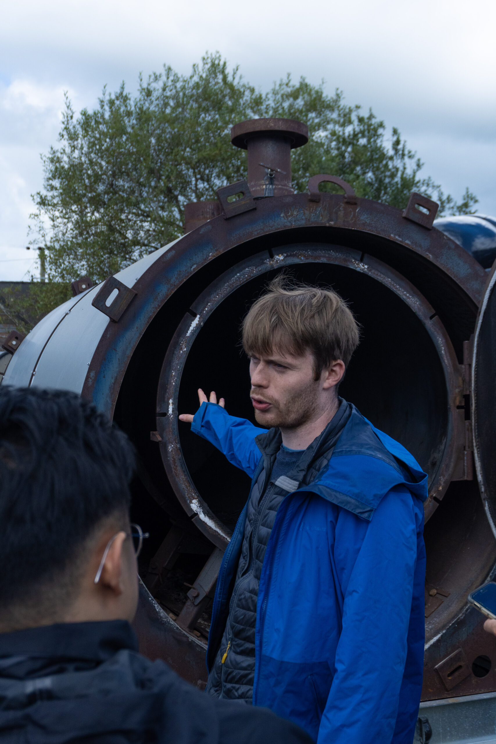 A person stands in front of an oven used to make biochar.