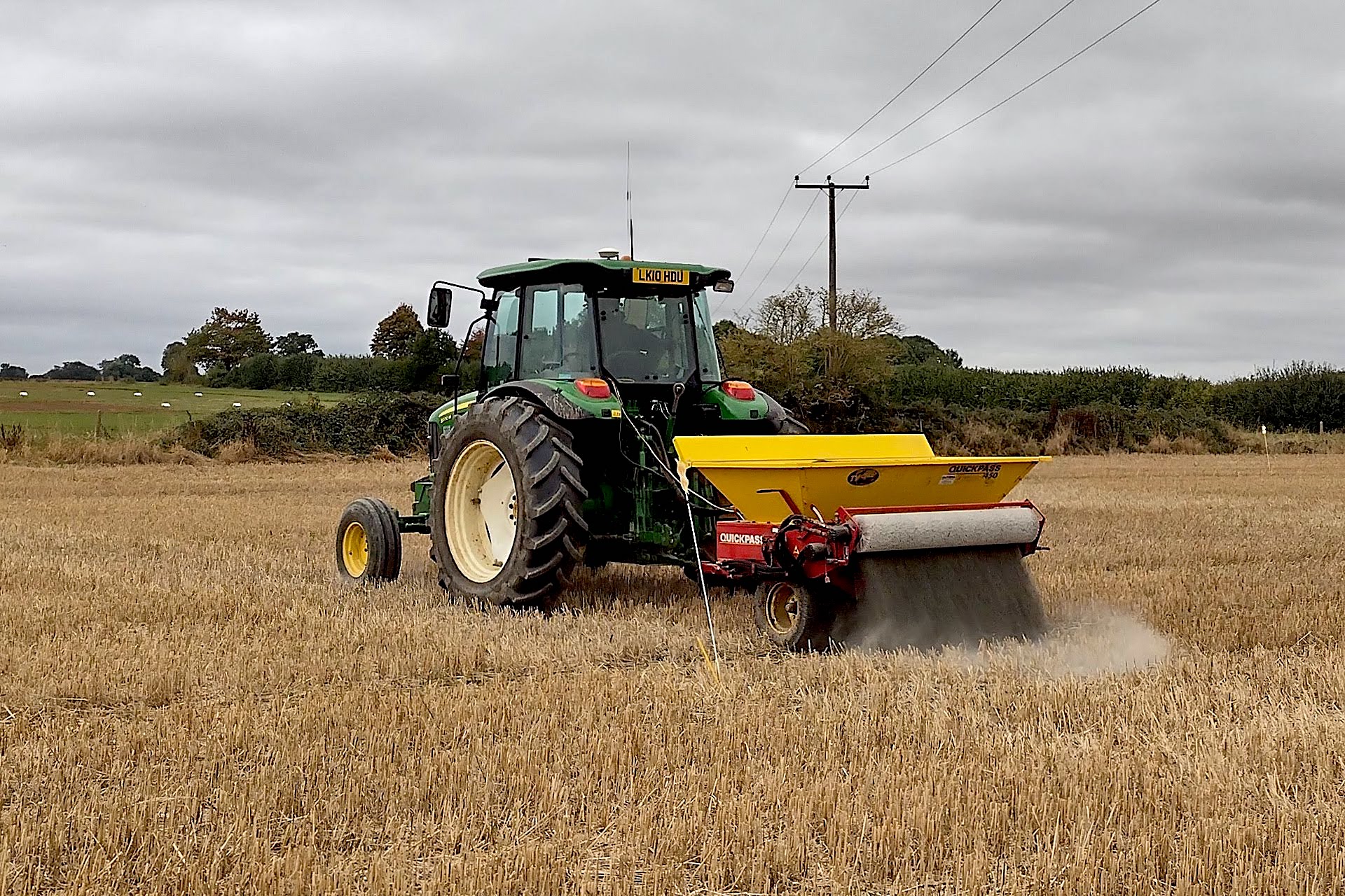 Tractor lays crushed rock onto field