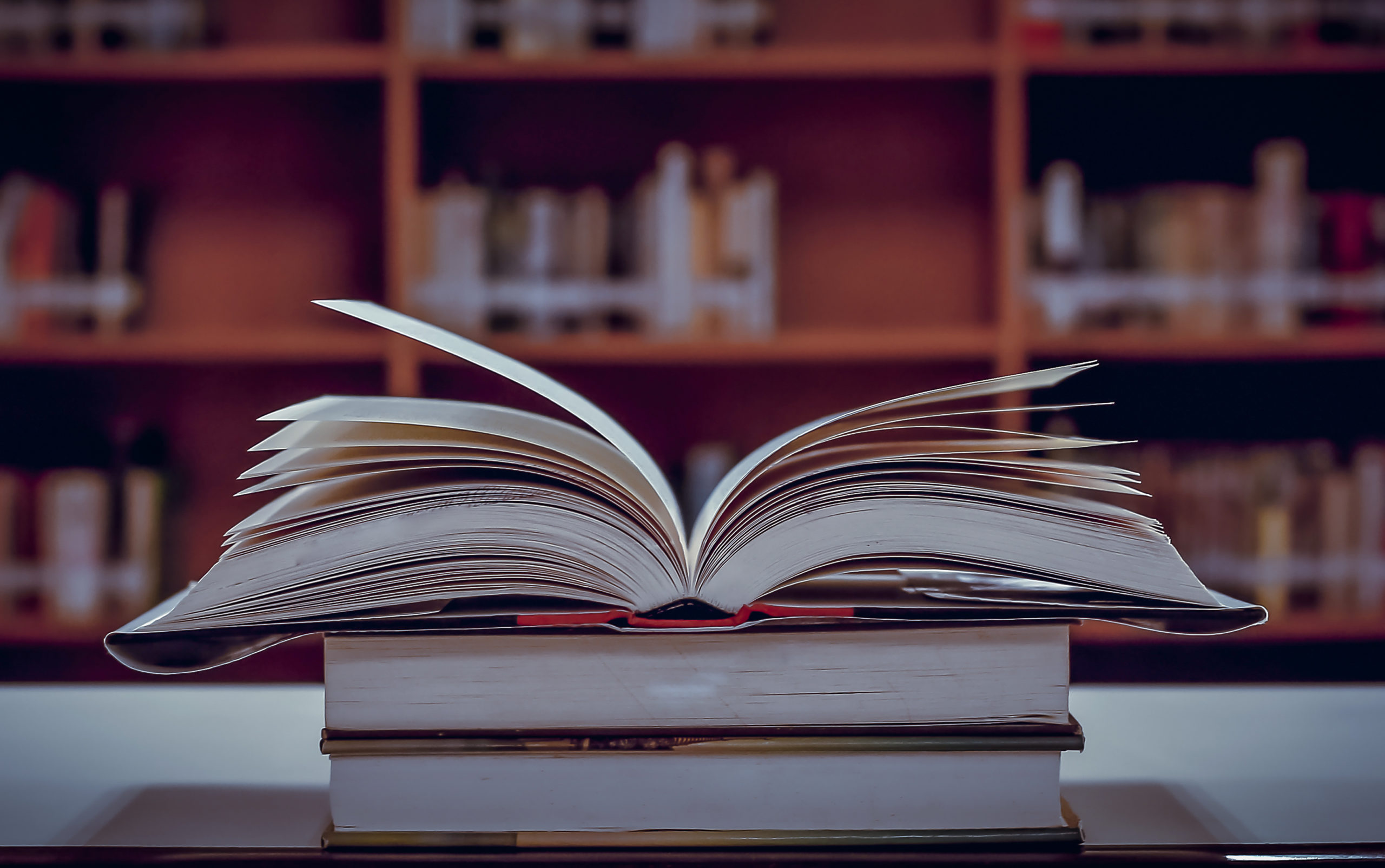 Stack of books in the library and blur bookshelf background