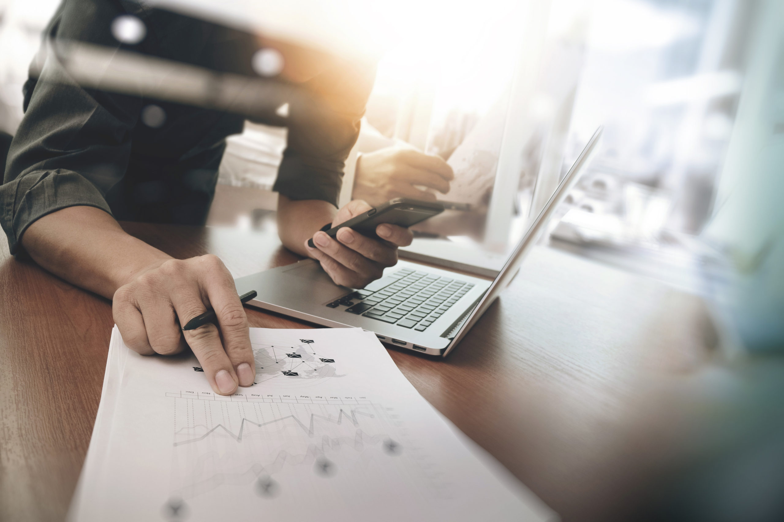 business man hand working on laptop computer with digital layer business graph information diagram on wooden desk as concept