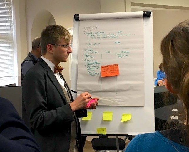 Man at sandpit event writing on whiteboard