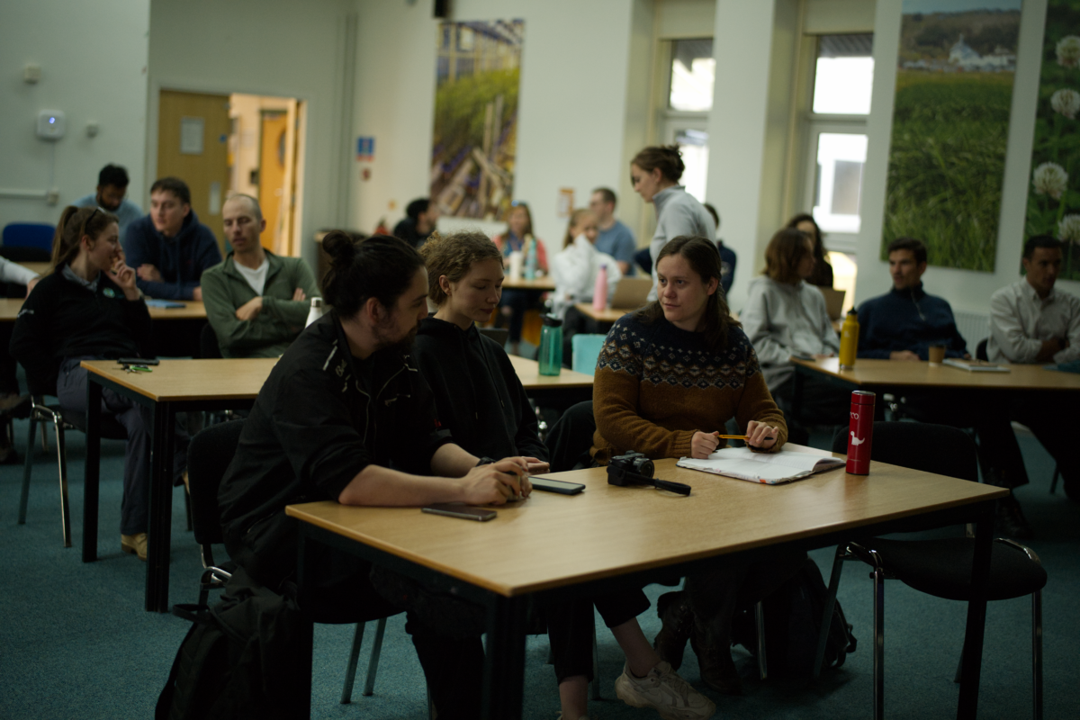 People sitting at desks and talking in a classroom.